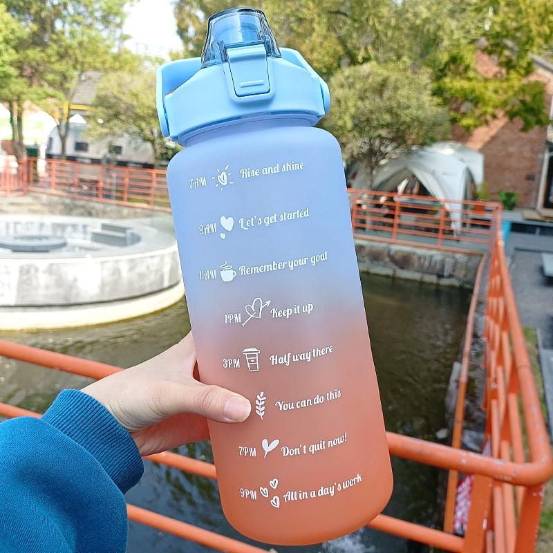 Gradient water bottle with motivational phrases held by a person outdoors.