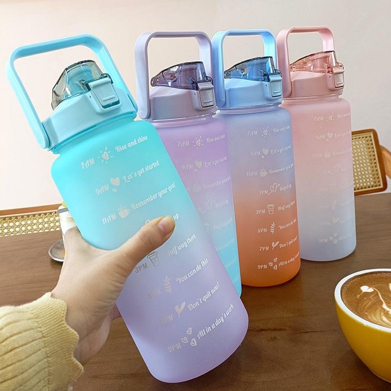 Set of colorful water bottles with handles on a wooden surface.