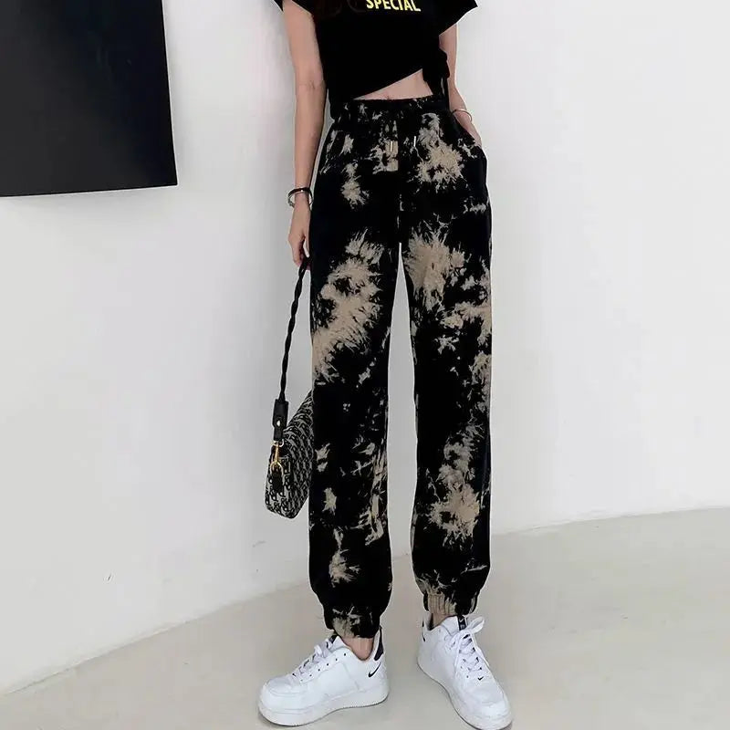 Person wearing tie-dye pants with a plain background