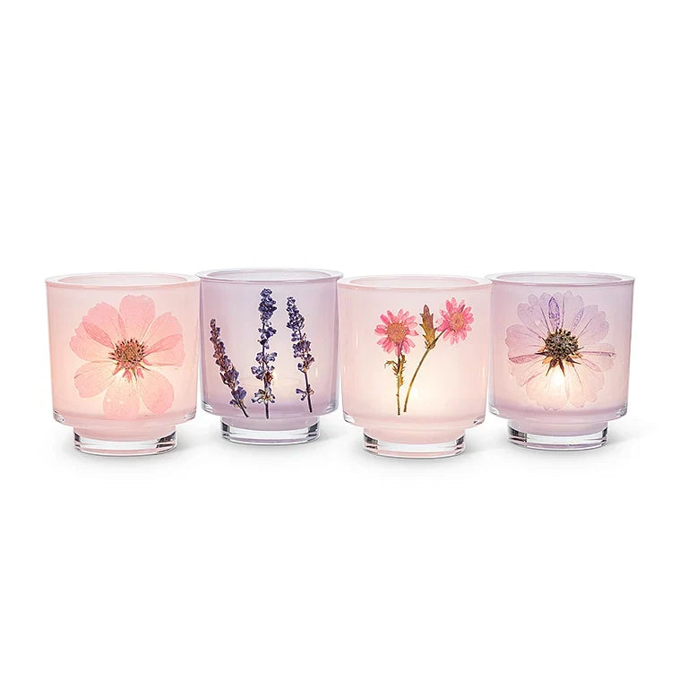 Four glass candle holders with floral designs on a white background