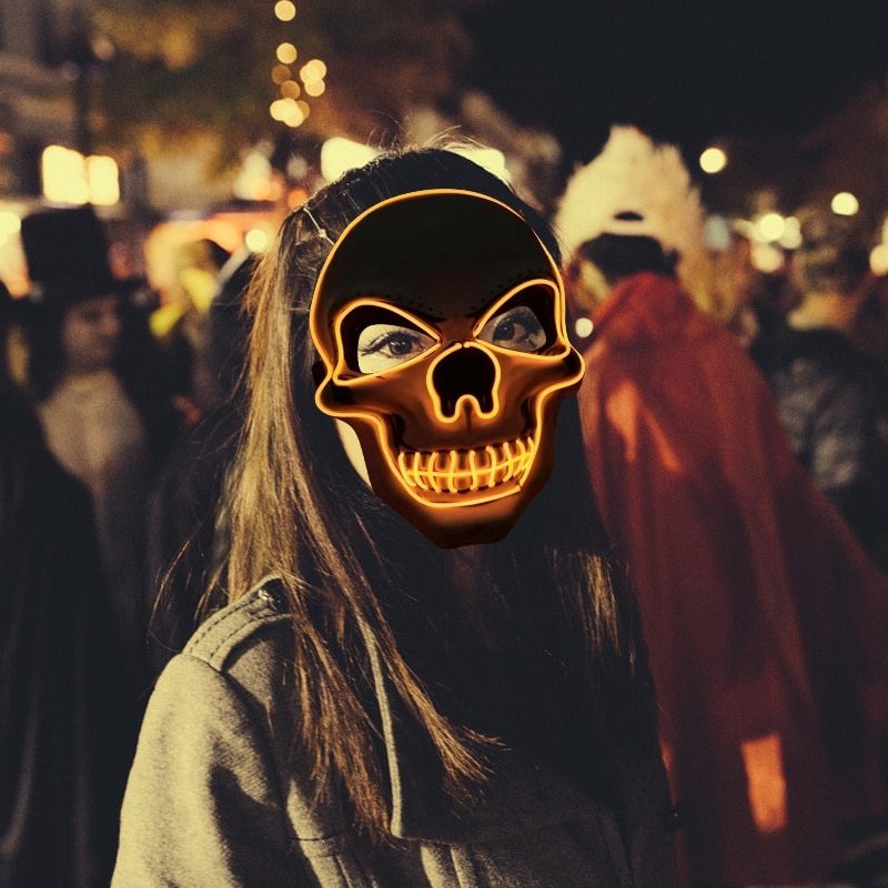 Person wearing a glowing skull mask in a crowd at night