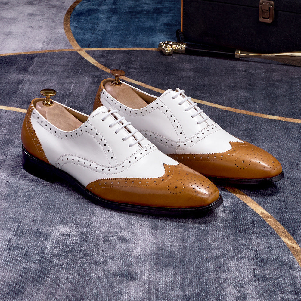 White and brown dress shoes on a textured surface with a suitcase in the background