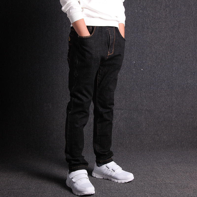 Person wearing black jeans and white sneakers on a dark background