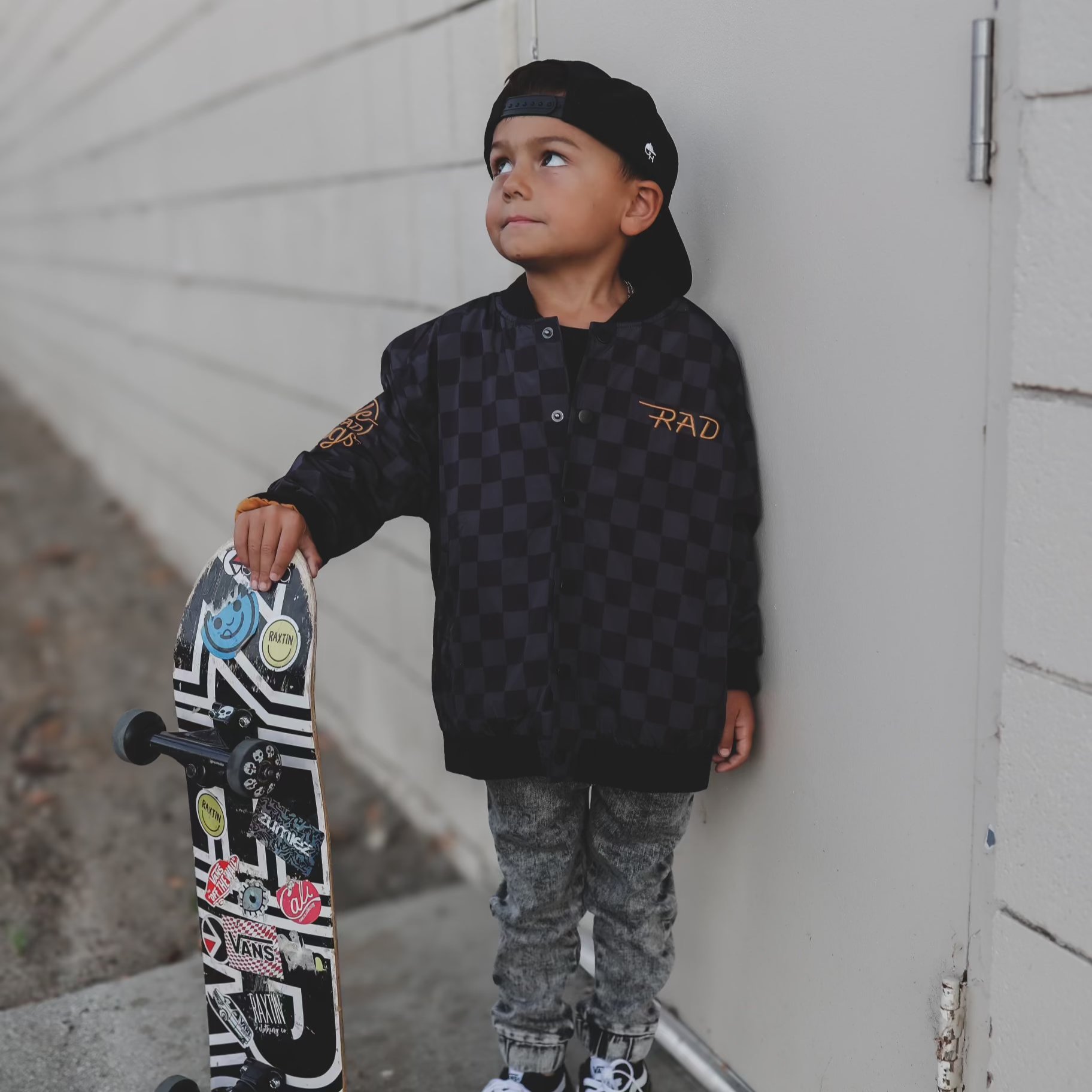 Child holding a skateboard against a neutral background