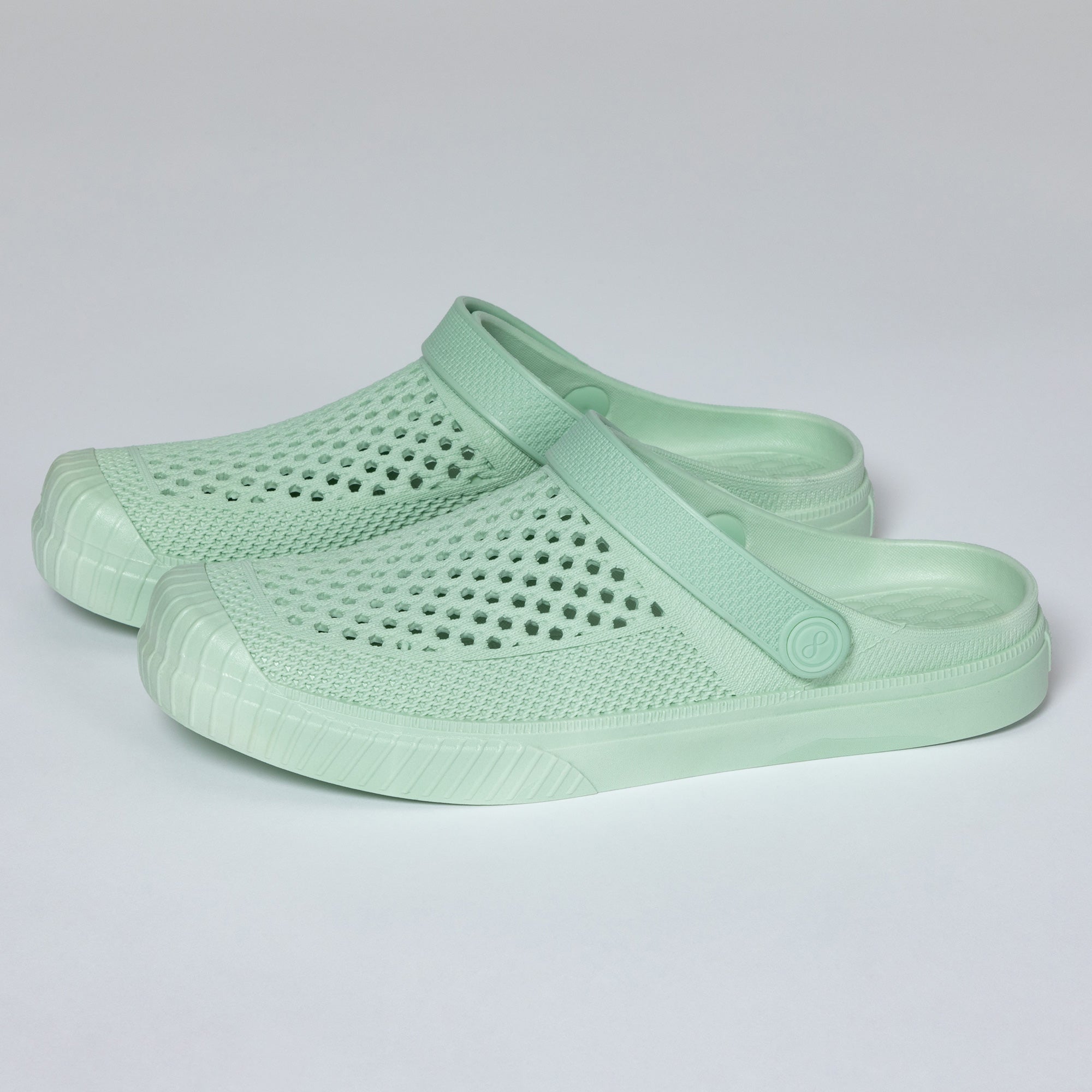 Pair of light green clogs on a gray background