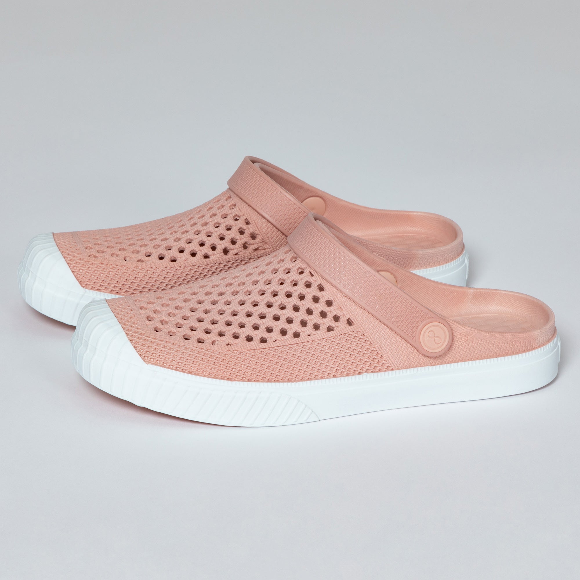 Pair of pink clogs with white soles on a light gray background