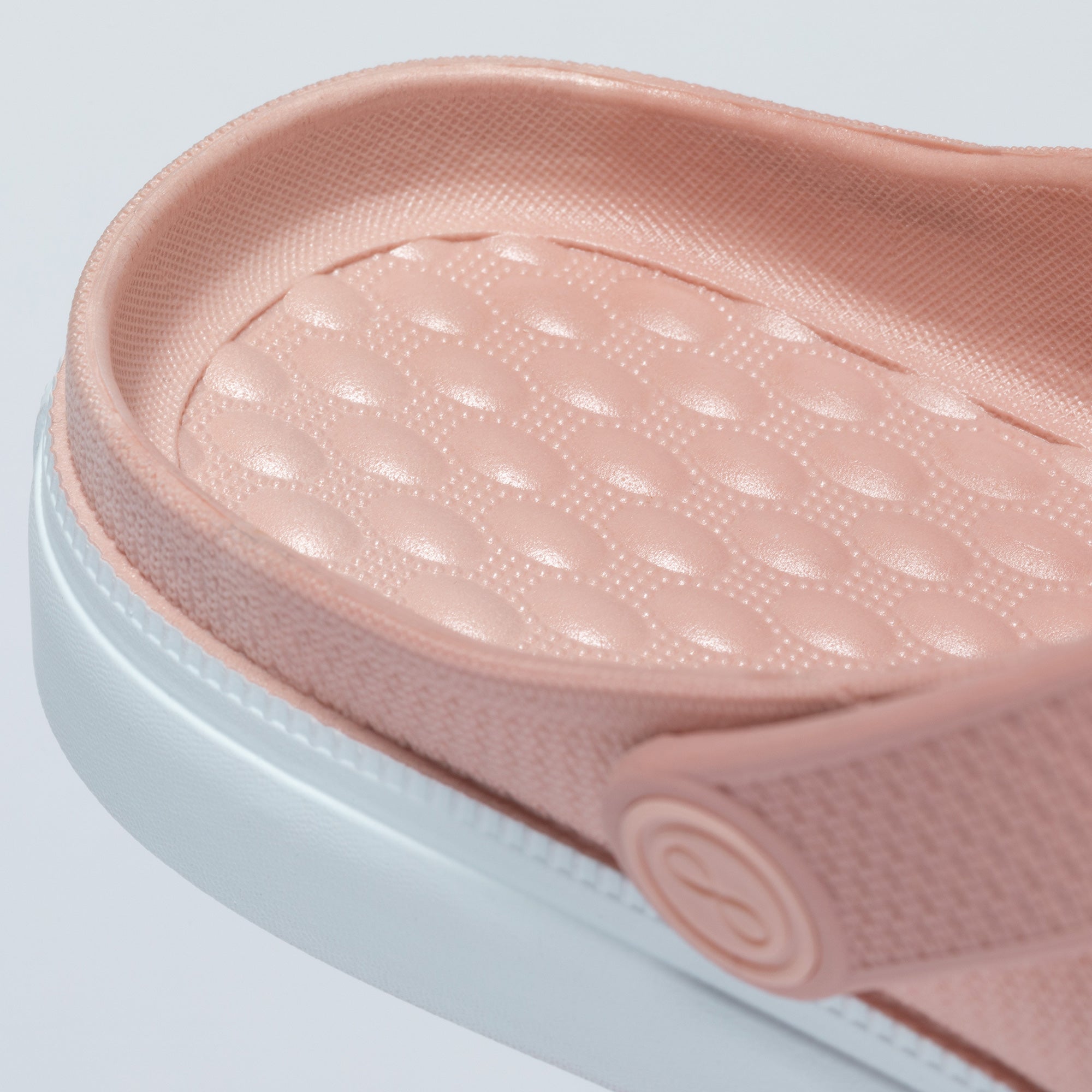 Close-up of a pink slide sandal with a light blue sole on a light gray background