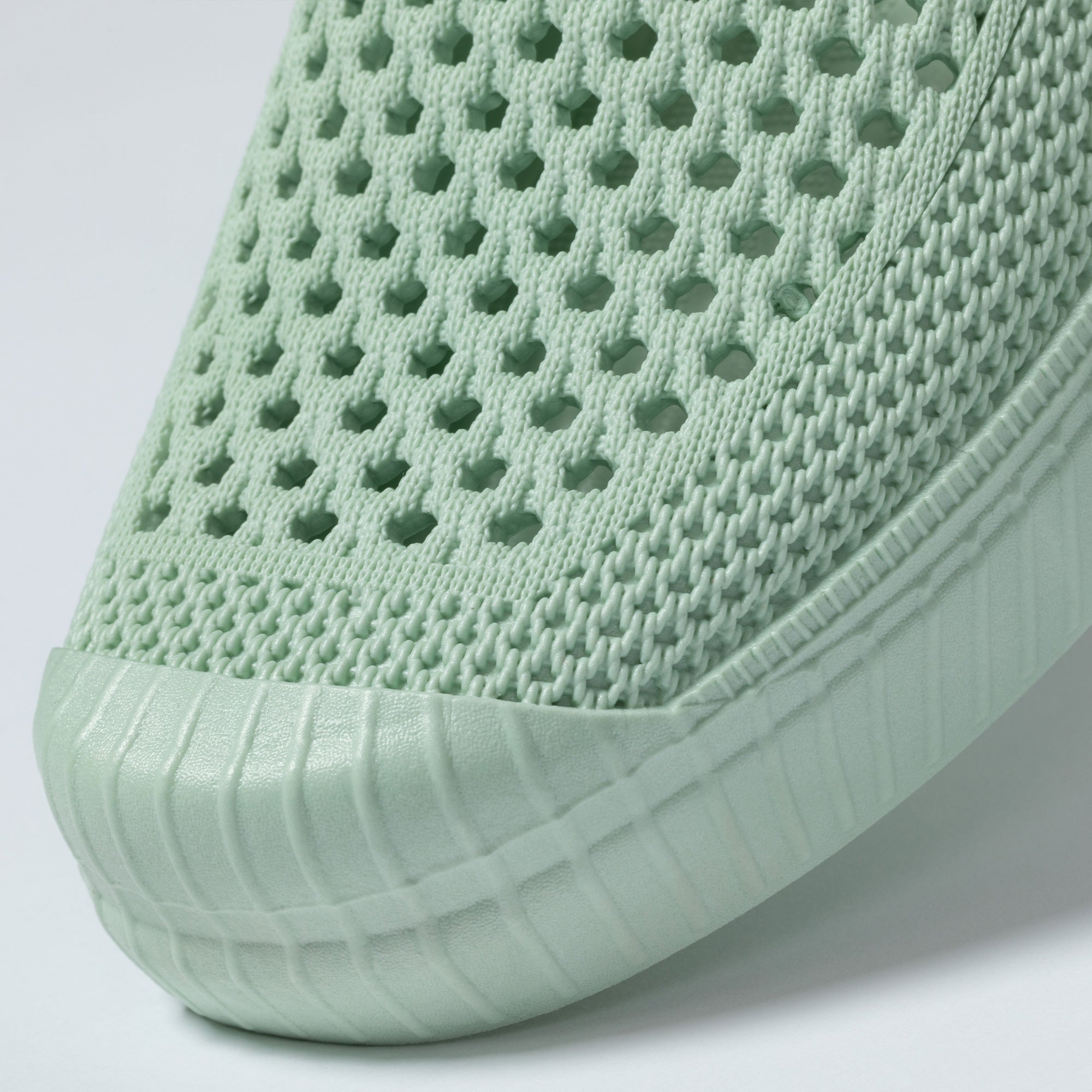 Light green slip-on shoe with textured surface on a white background