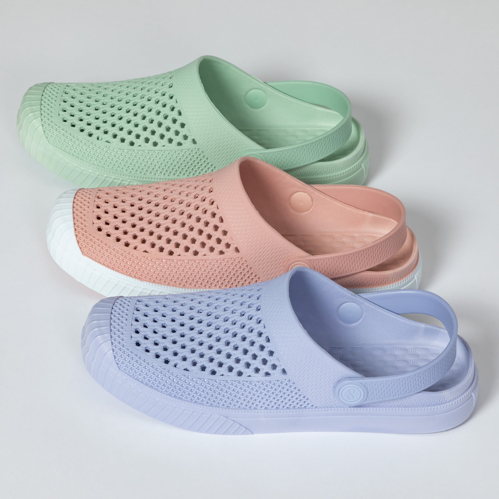 Three pairs of mesh sandals in green, pink, and blue on a light gray background