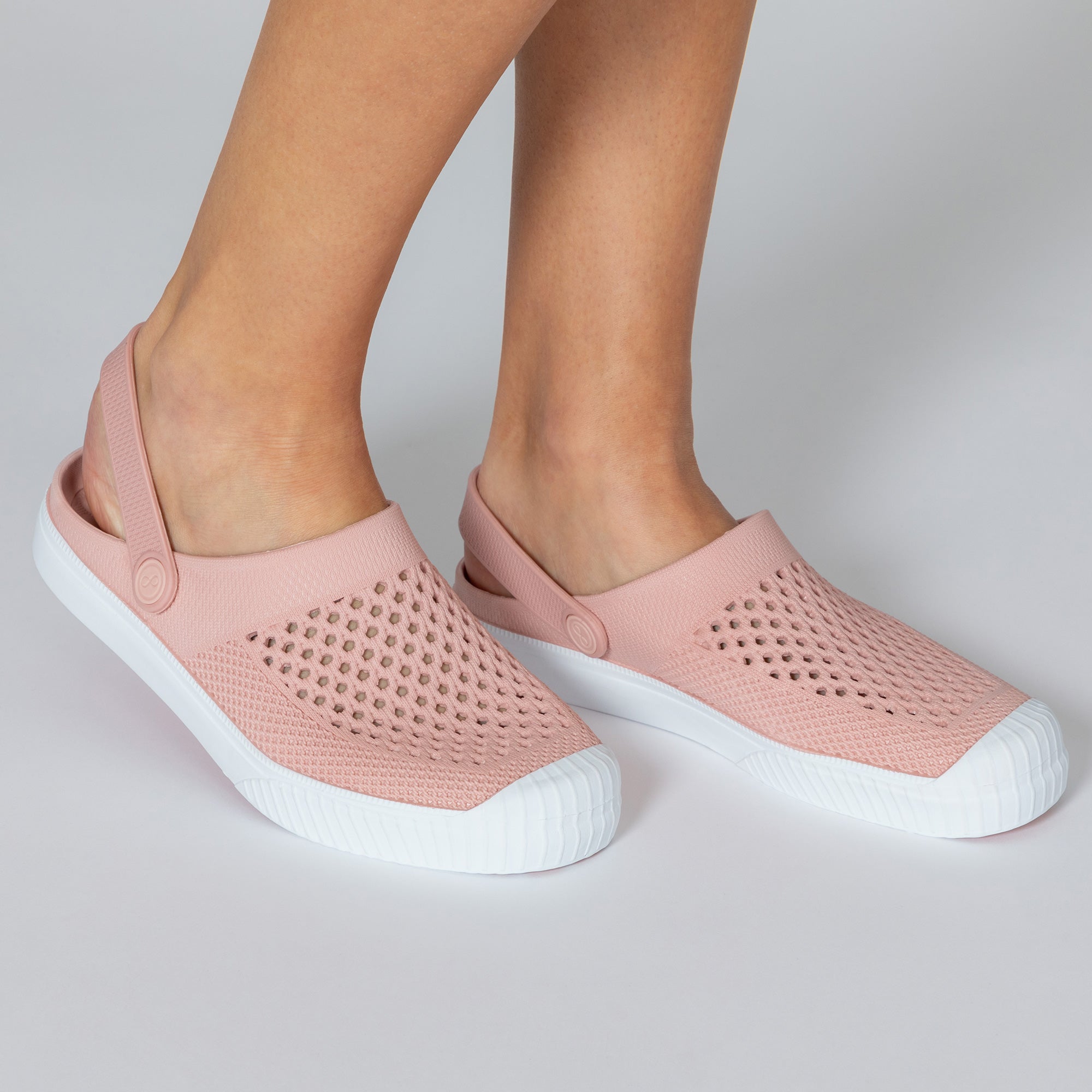 Pink clogs with white soles on a neutral background