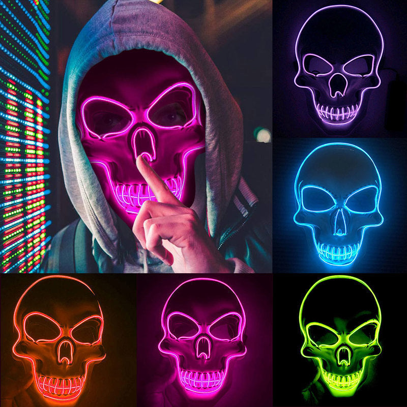 Person wearing a hoodie with a glowing pink skull mask, surrounded by other colorful skull masks.