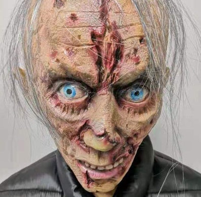 Person with detailed makeup resembling a zombie or alien creature on a plain background