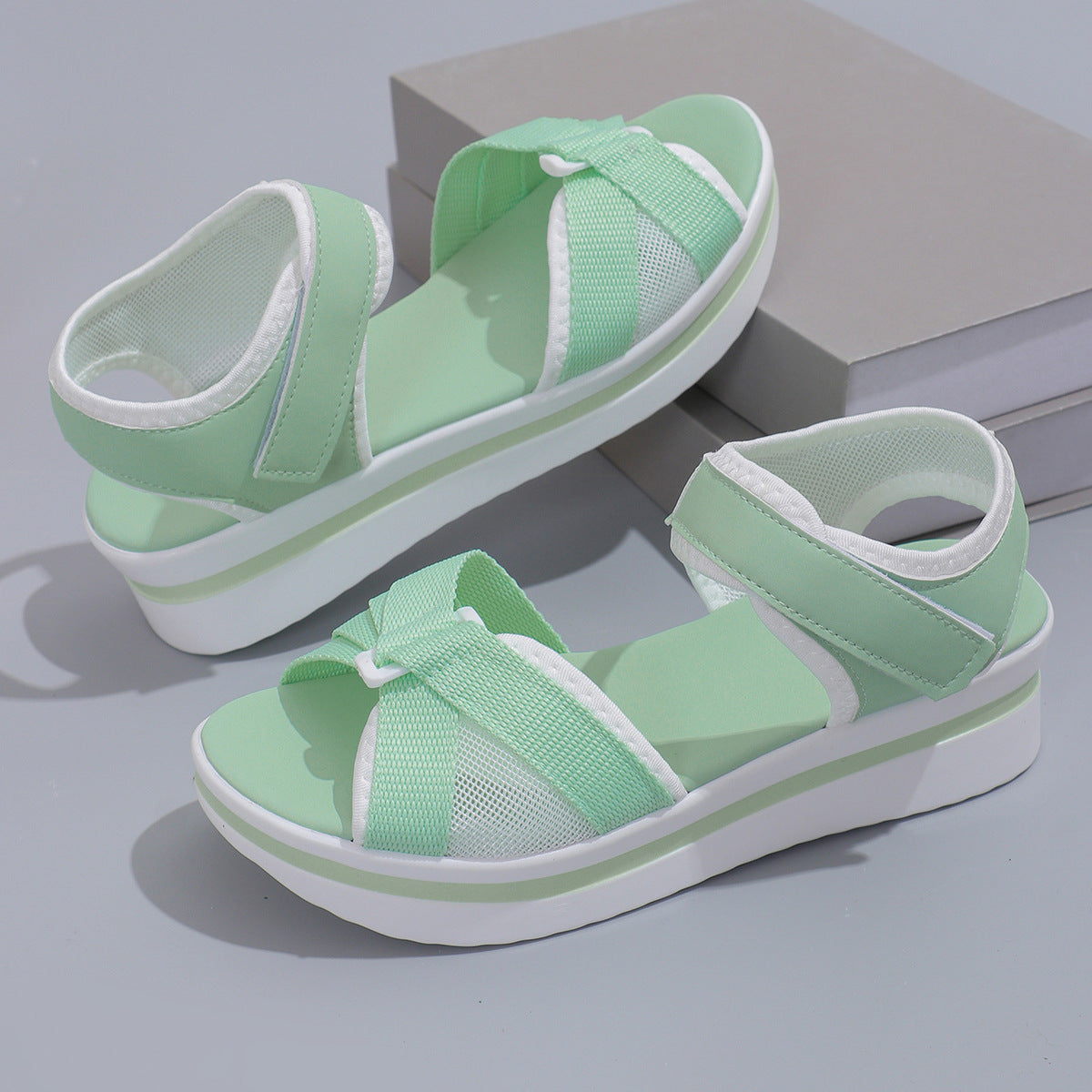 Pair of green sandals with white straps on a gray background