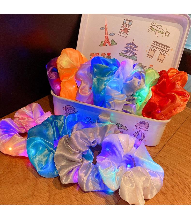 Colorful LED scrunchies in a container on a wooden surface