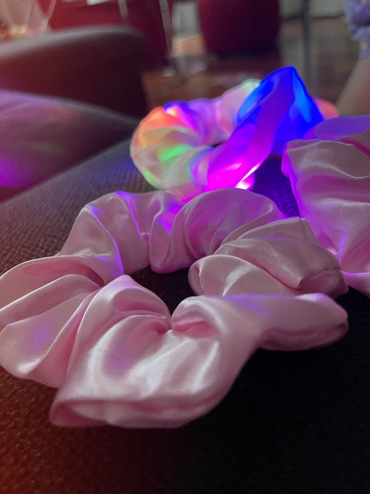 Pink scrunchies with LED lights on a dark surface