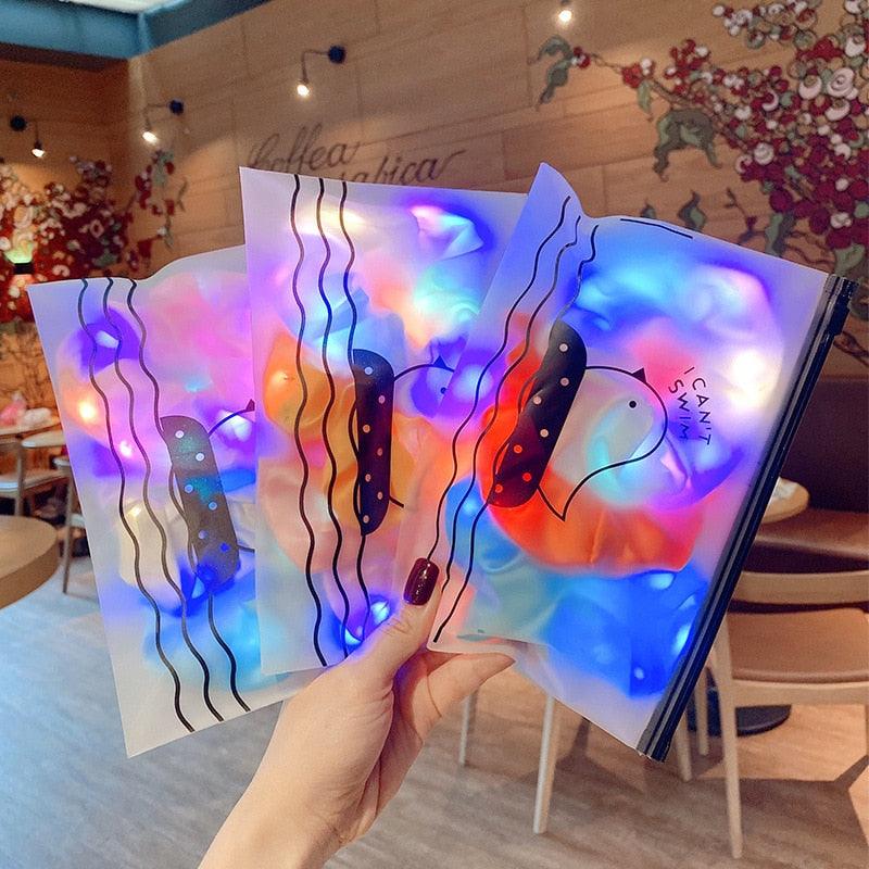 Colorful stained glass art pieces held by a hand in an indoor setting.
