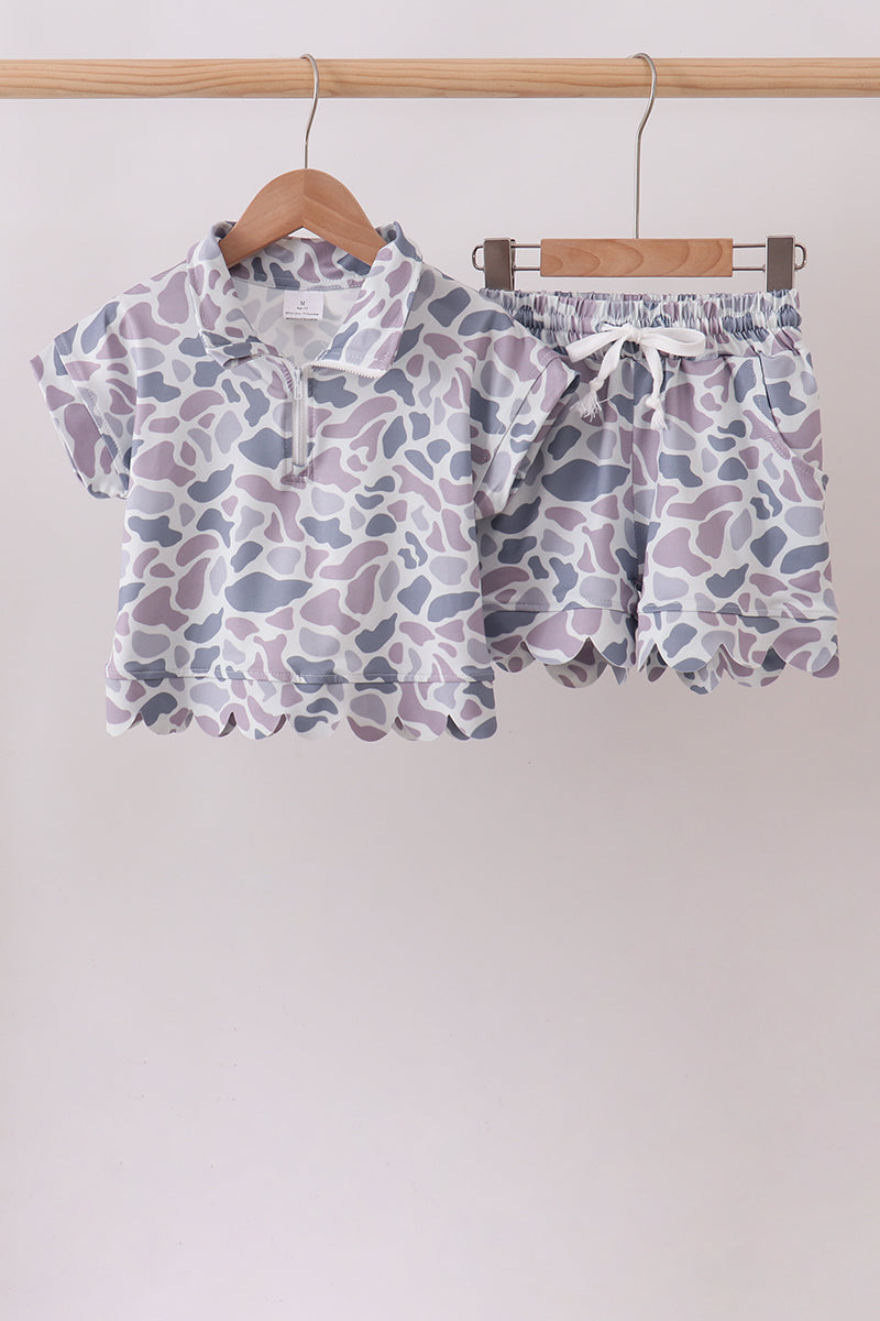Purple patterned shirt and shorts set on hangers against a white background