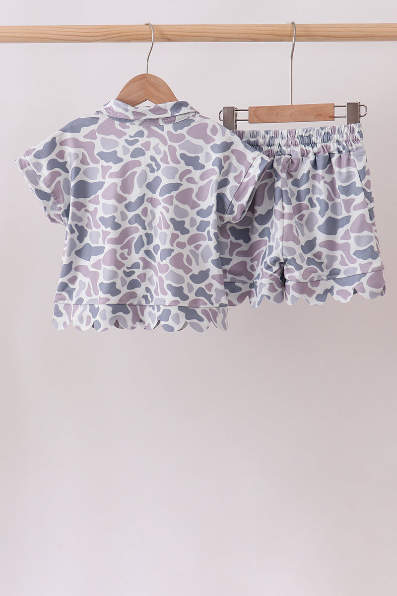 Children's outfit with a patterned shirt and shorts on a hanger against a white background