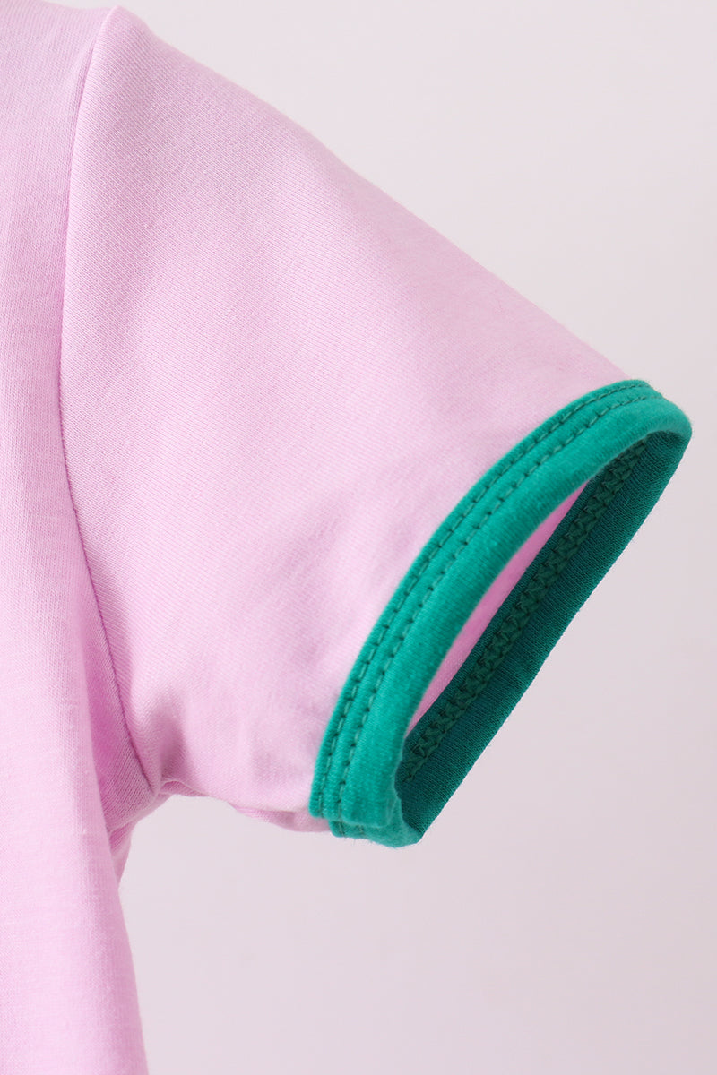 Close-up of a pink garment with green trim on a light gray background