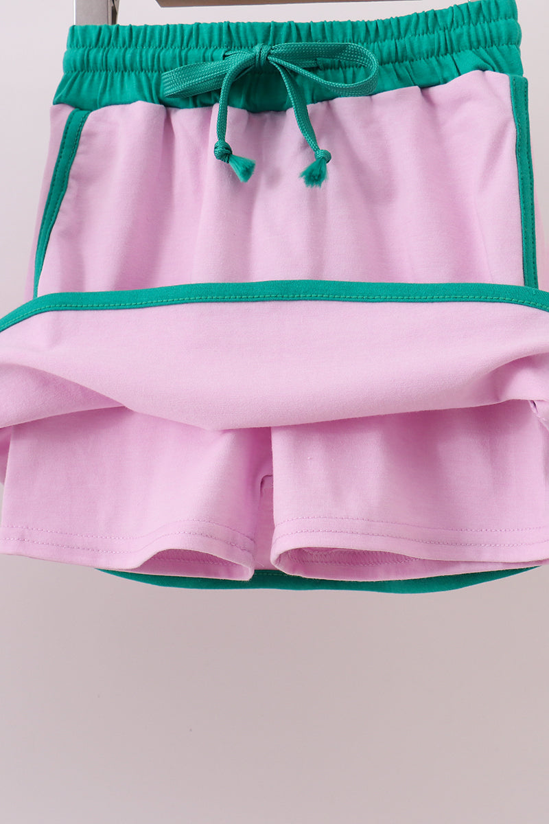 Pink shorts with green trim on a light gray background