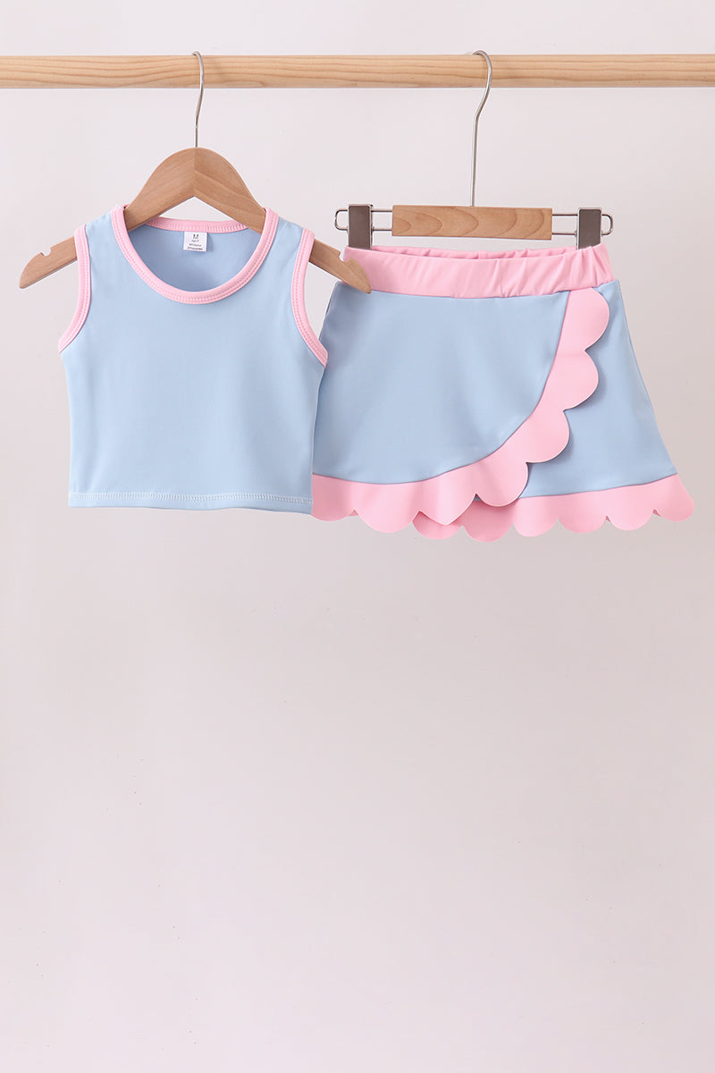 Children's light blue top and pink shorts set on a wooden hanger against a plain background