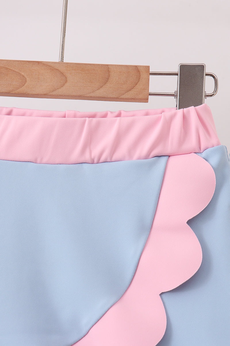 Pink and blue skirt on a hanger against a light gray background