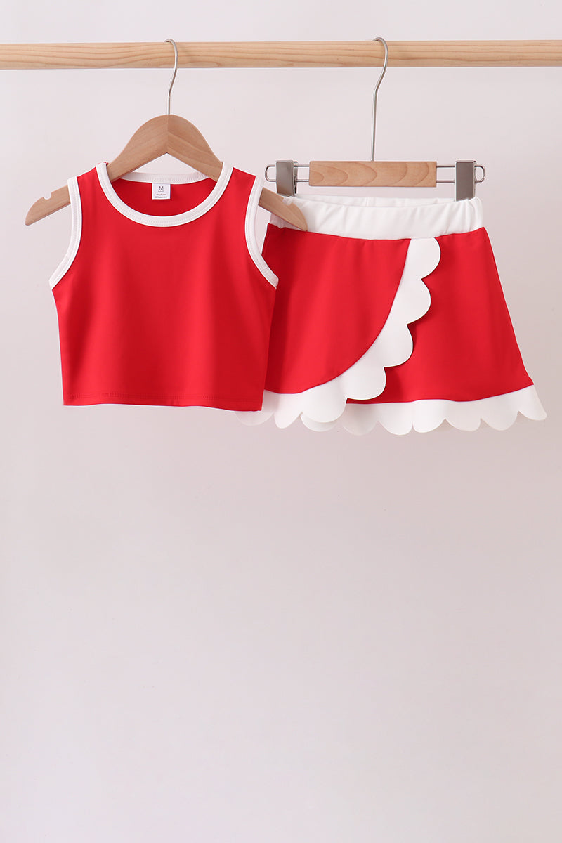 Red tank top and skirt set with white trim on hangers against a light background