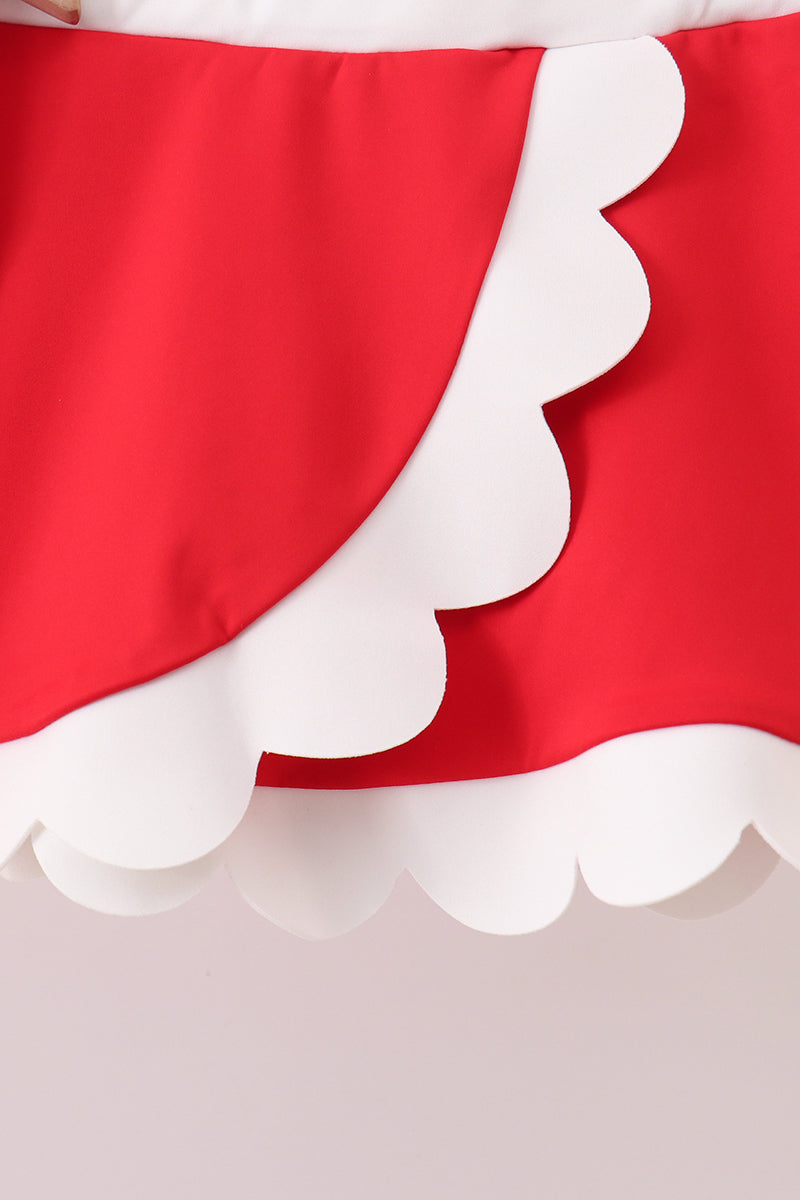 Close-up of a red fabric with white scalloped edge on a light gray background
