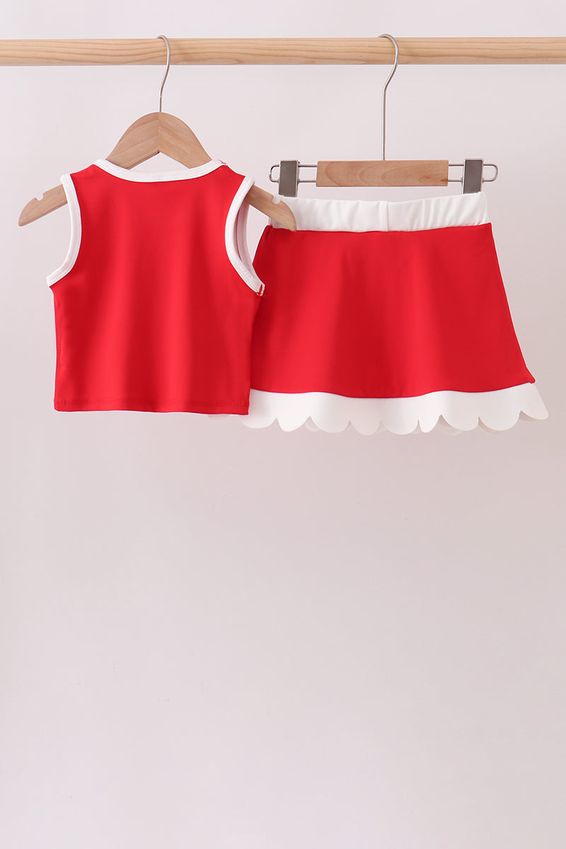 Red top and skirt set with white trim on hangers against a light background