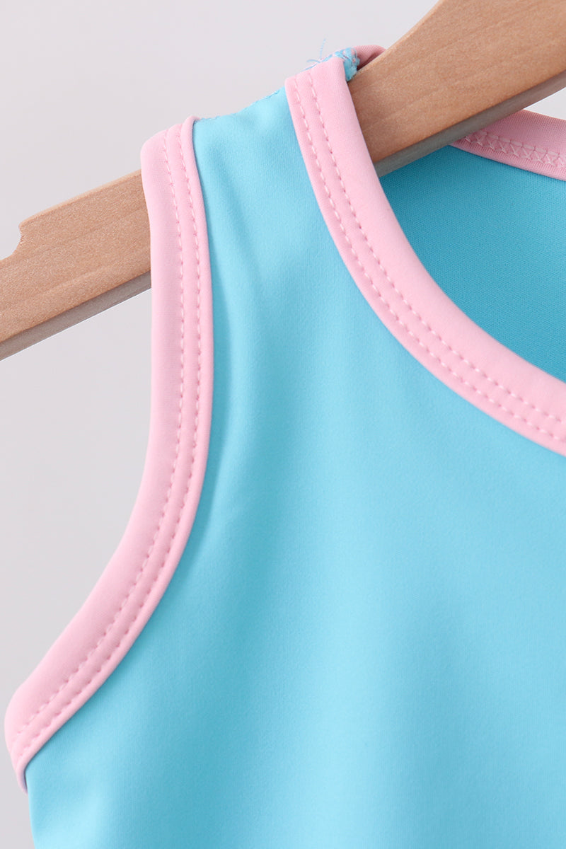 Light blue swimsuit with pink trim on a wooden hanger against a light gray background