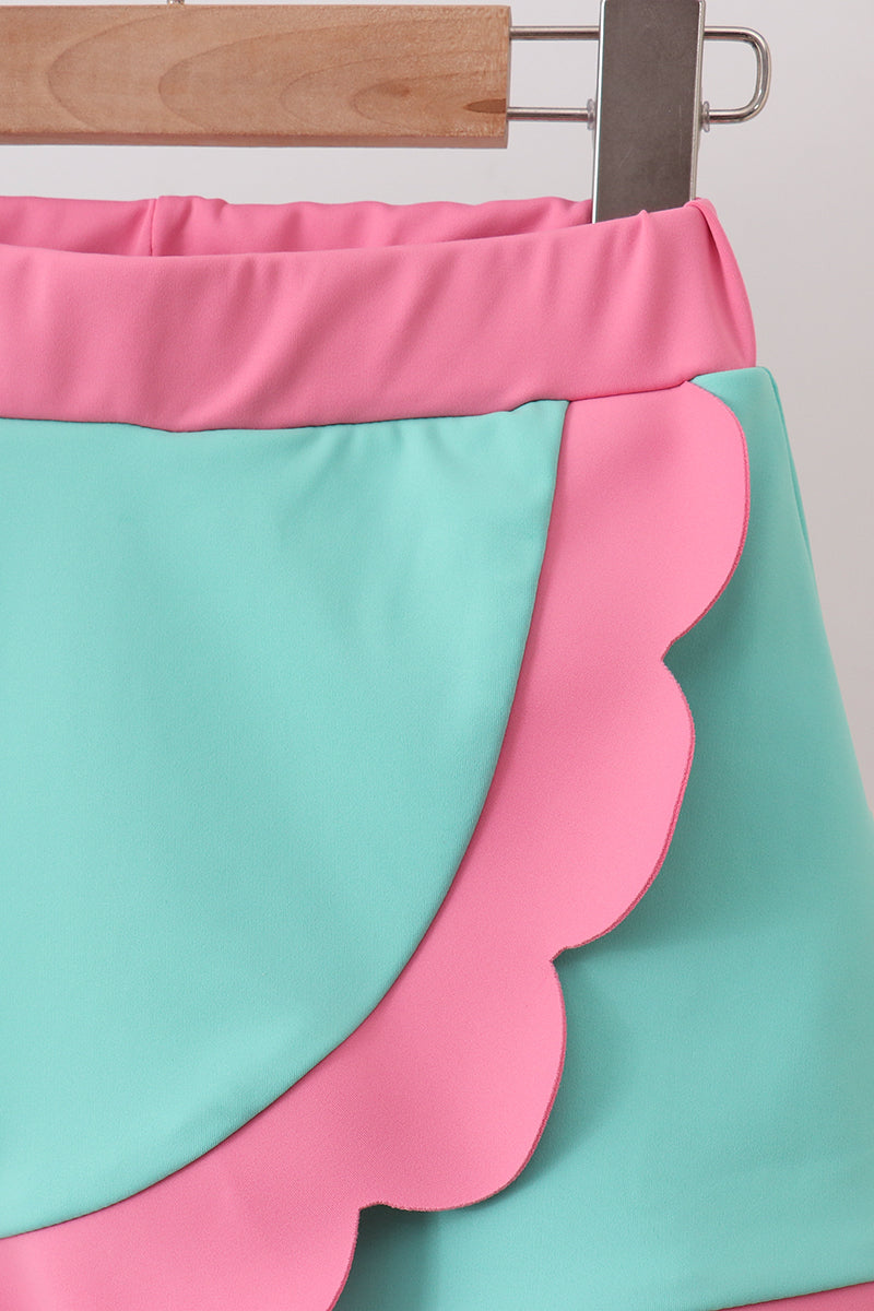 Close-up of a skirt with pink and green colors on a wooden hanger.