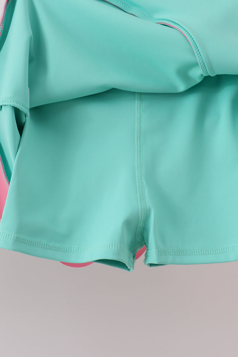 Teal swimsuit top and shorts on a neutral background