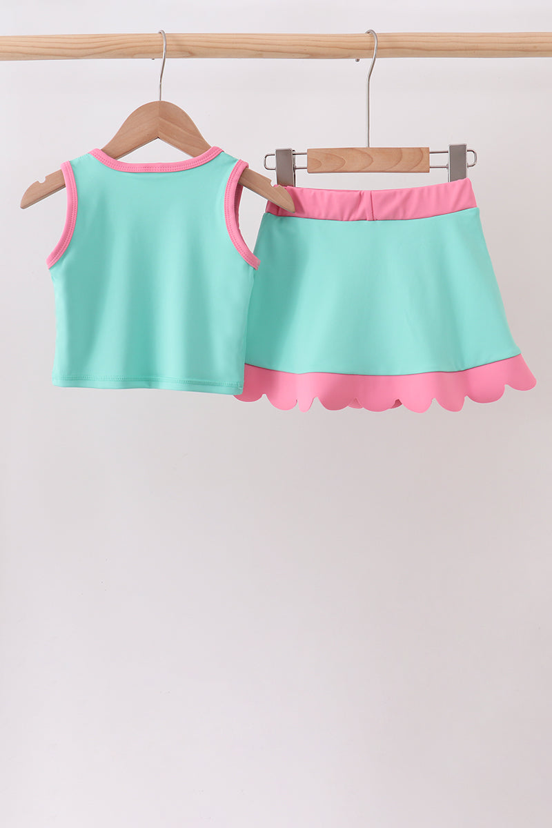 Children's outfit with a top and skirt on hangers against a light background