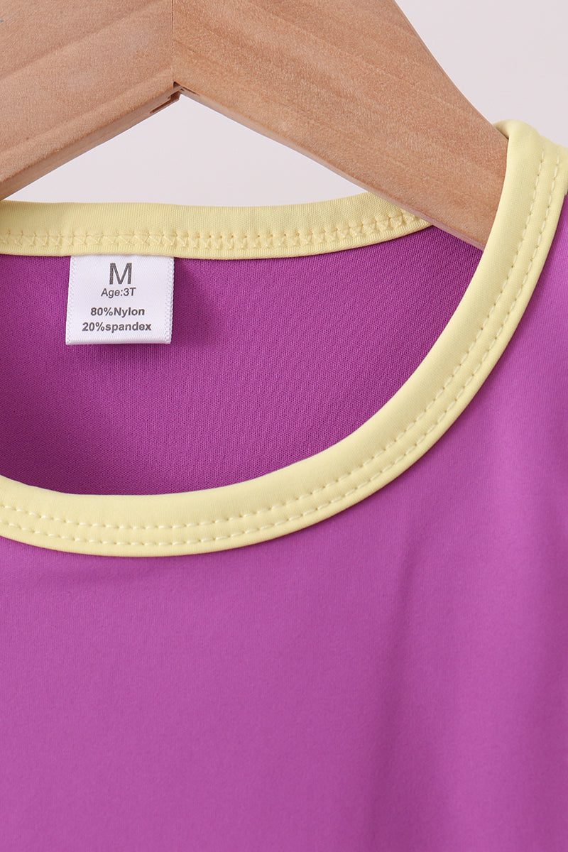 Purple garment with yellow trim on a hanger, showing fabric composition label.