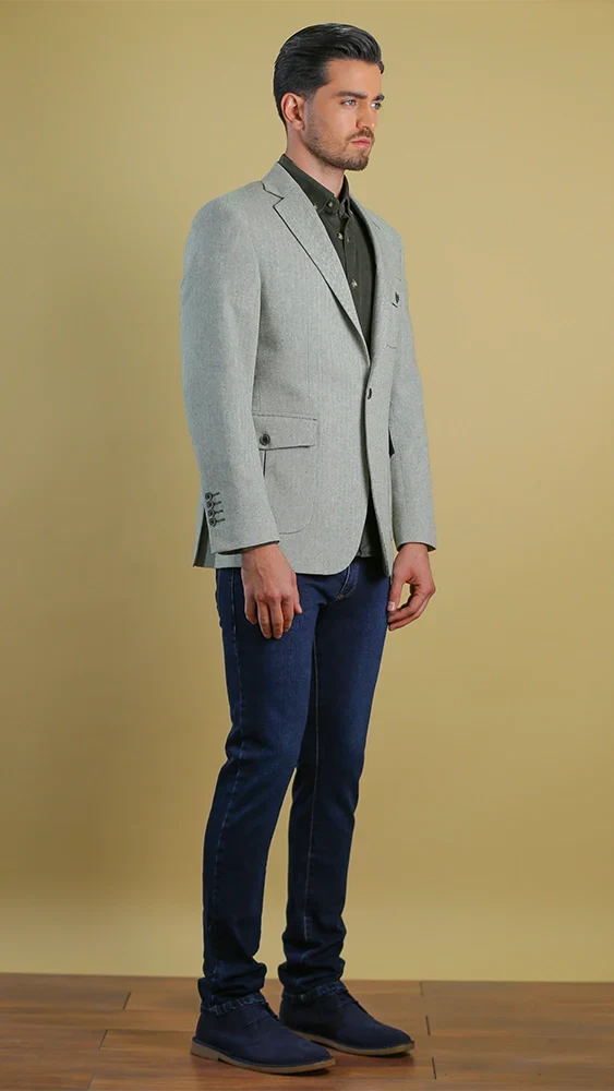 Man wearing a light gray blazer and dark blue pants against a beige background