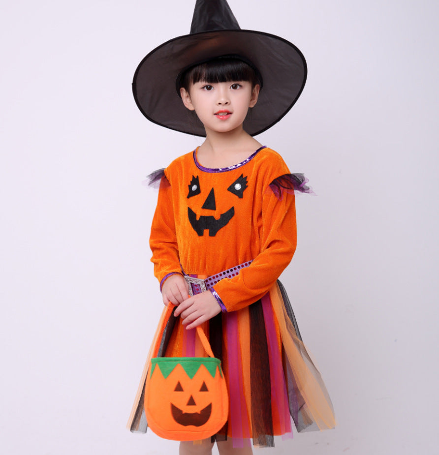 Child in Halloween costume with orange dress and witch hat holding a pumpkin bag.