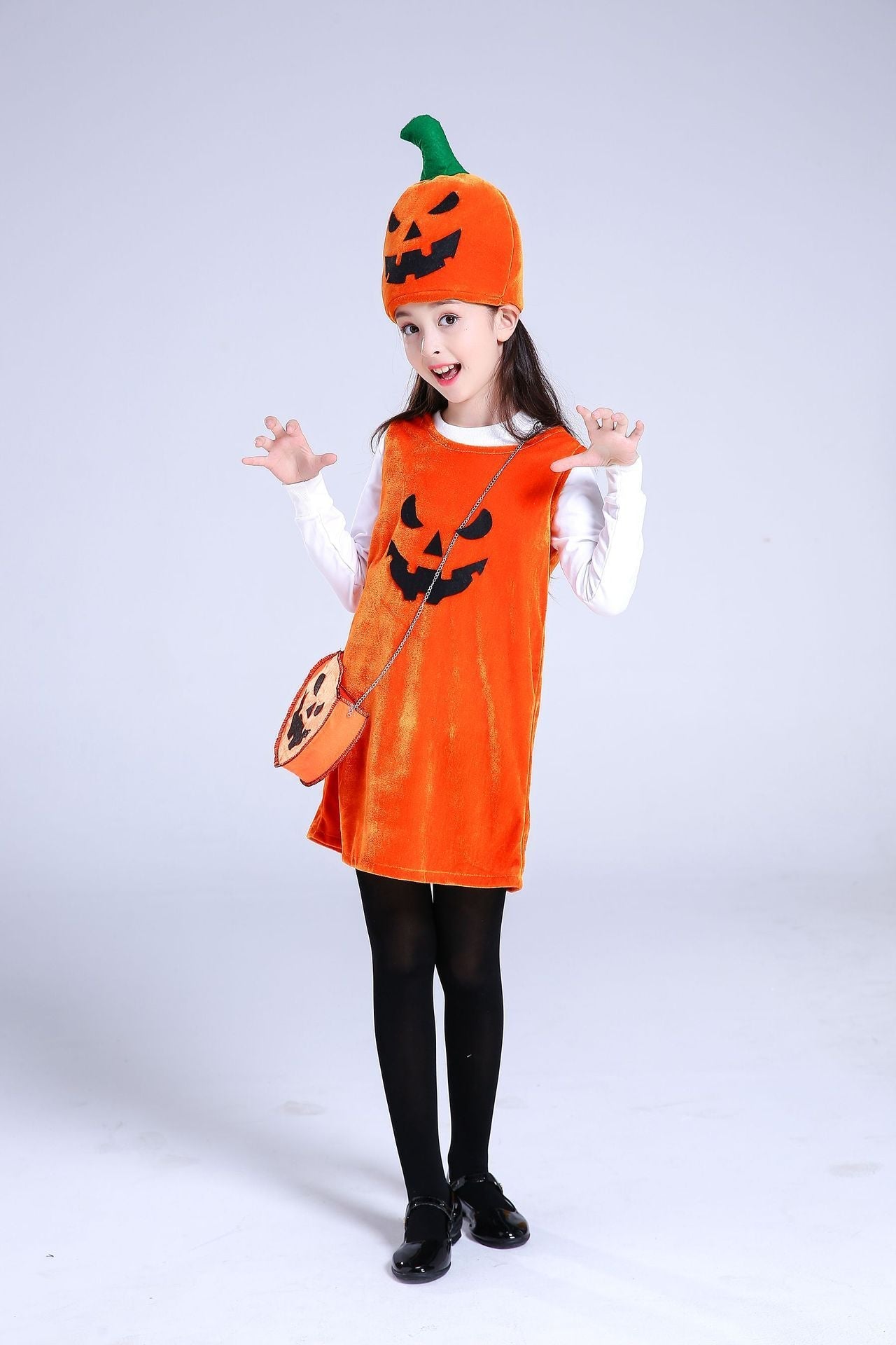 Child wearing an orange pumpkin costume with a hat and bag on a white background