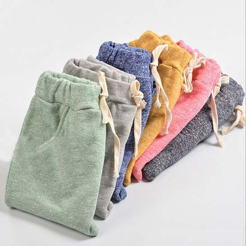 Stack of colorful drawstring pants on a light gray background