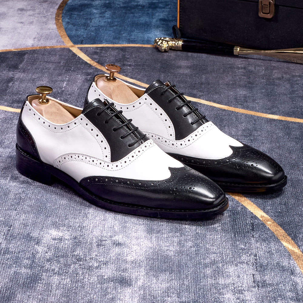 Black and white dress shoes on a textured surface with a suitcase in the background