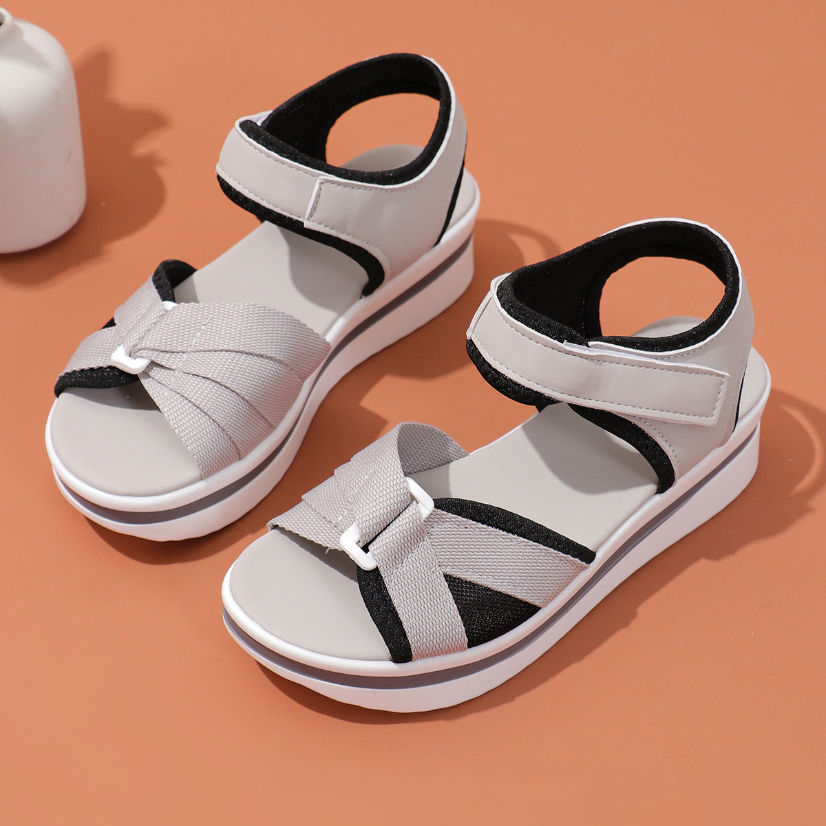 Pair of gray sandals with black straps on a brown background