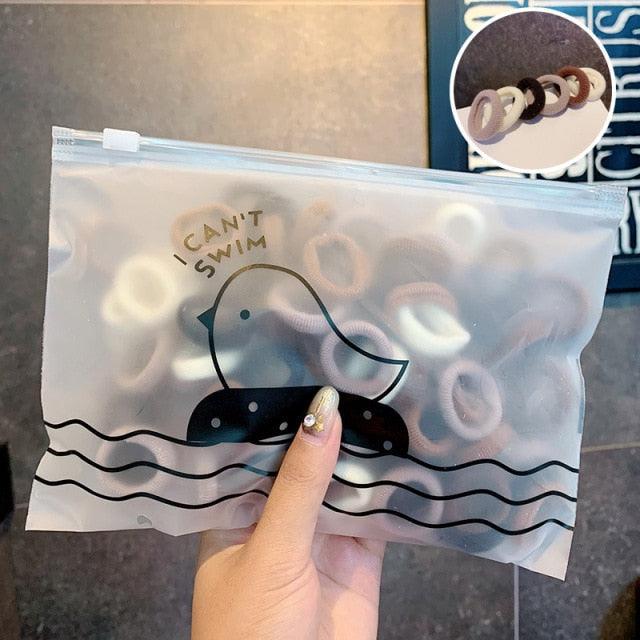 Clear plastic bag with a cartoon penguin design and text, held by a hand.
