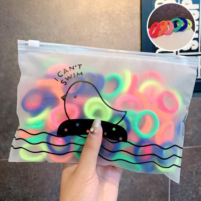 Clear bag with colorful rubber duckies and 'I Can't Swim' text, held by a hand.