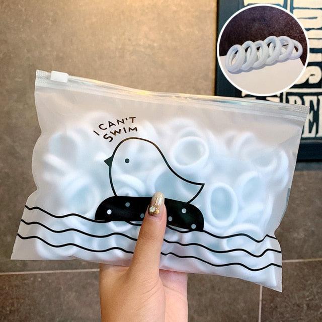 Silicone earbud storage bag with a cartoon duck design and text 'I Can't Swim' held by a hand.