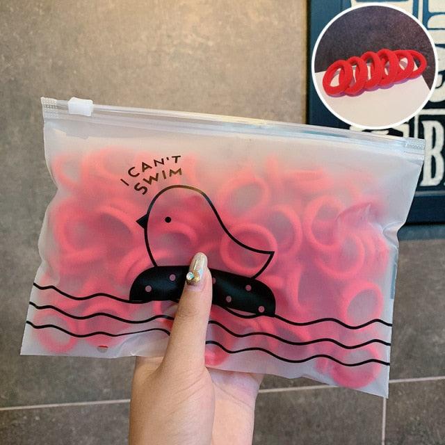 Clear bag with red rubber duckies and 'I Can't Swim' text, held by a hand.