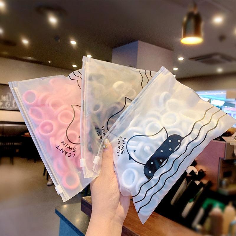 Three clear plastic bags with printed designs held by a person in an indoor setting.