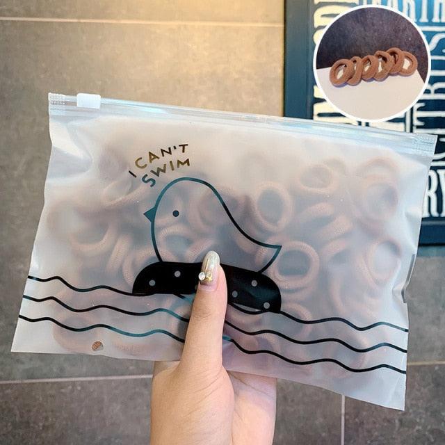 Clear plastic bag with a cartoon duck design and text, held by a hand.