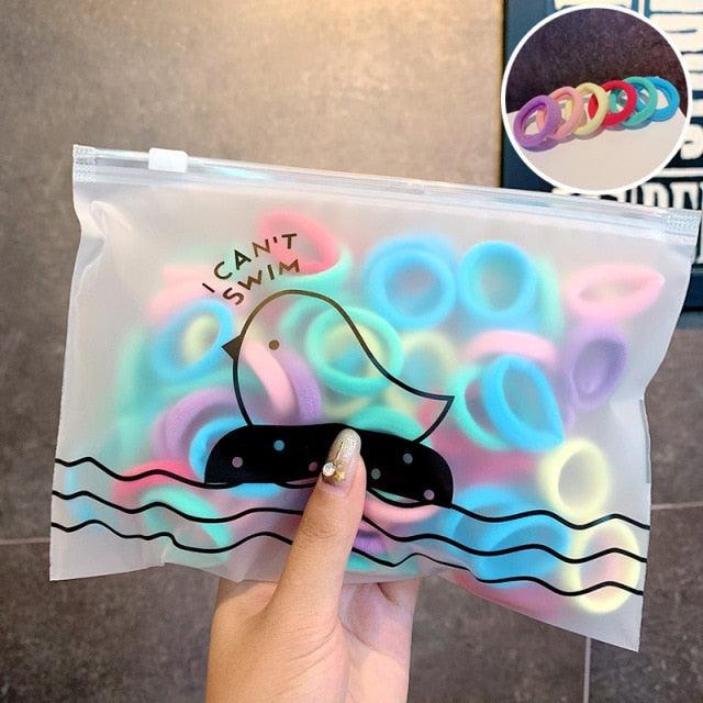 Packaged colorful rubber bands with a humorous label held by a hand.