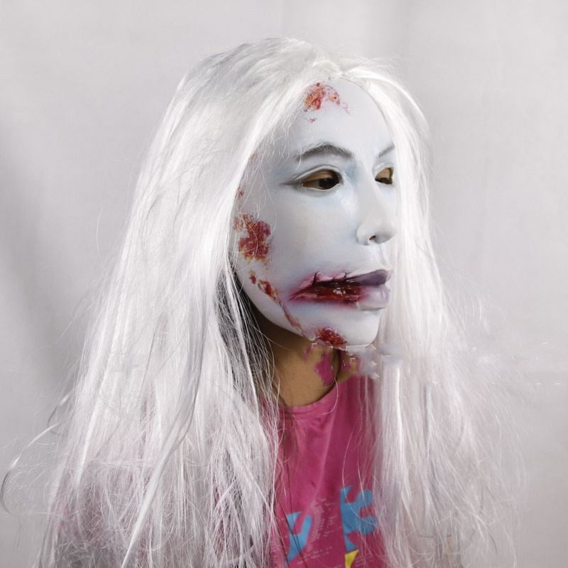 Person with white wig and zombie makeup wearing a pink shirt with colorful designs.