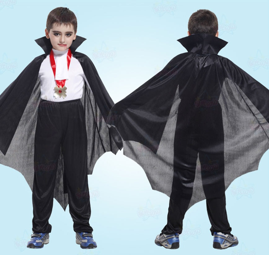 Child wearing a vampire costume with a cape and bat wings on a light blue background