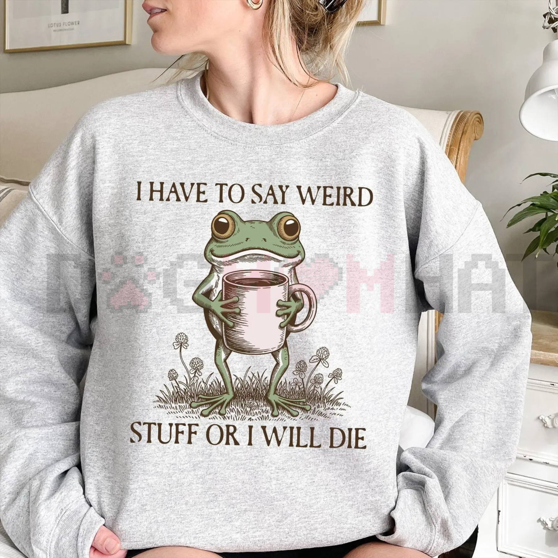 Person wearing a gray sweatshirt with a frog holding a mug design and text.